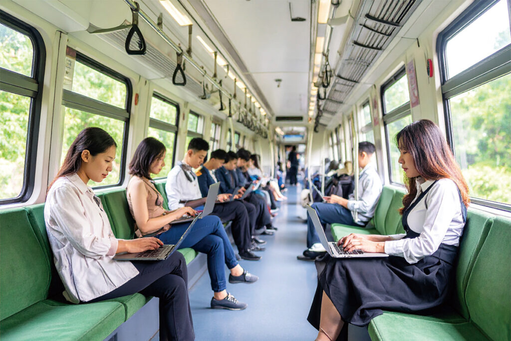 Commuters working on laptops inside a quiet Green Car train carriage in Japan, turning a long commute into productive work time