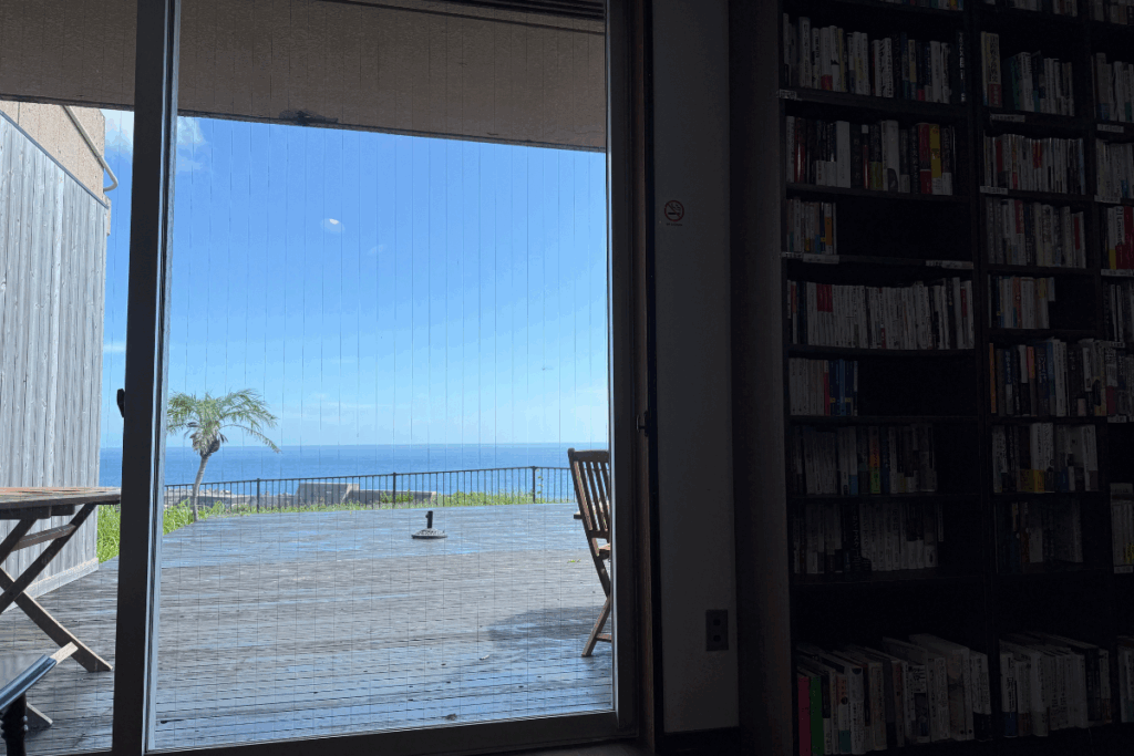 A sunny window view framed by a palm tree, capturing the laid-back island vibe of Hachijojima’s local eateries