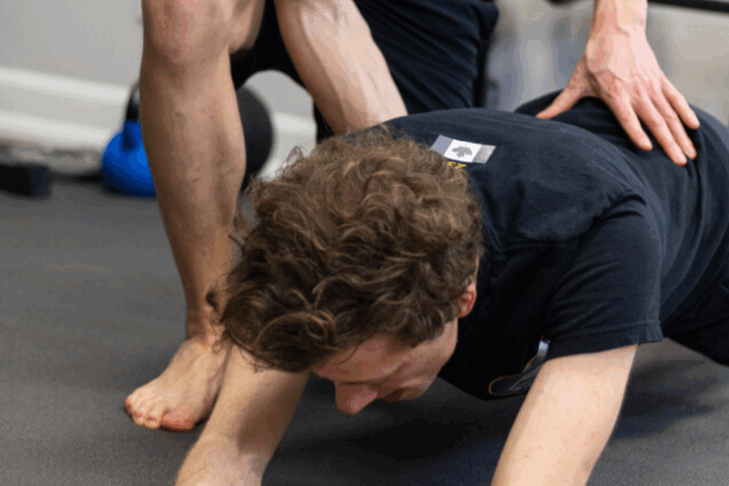 Personal trainer assisting an individual during an exercise session to ensure safe and effective movement