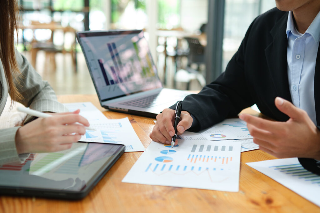 Two professionals review property ownership financials and discuss property investment strategy during a meeting.