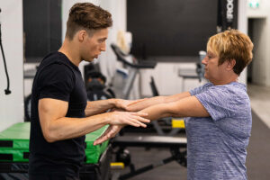 Summit fitness trainer assisting woman with exercise routine