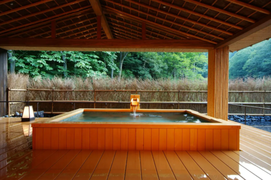 Luxurious private outdoor hot spring bath in Kinosaki Onsen surrounded by nature.