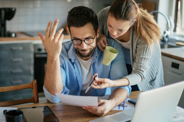 Young couple going over bills and payments together in the kitchen