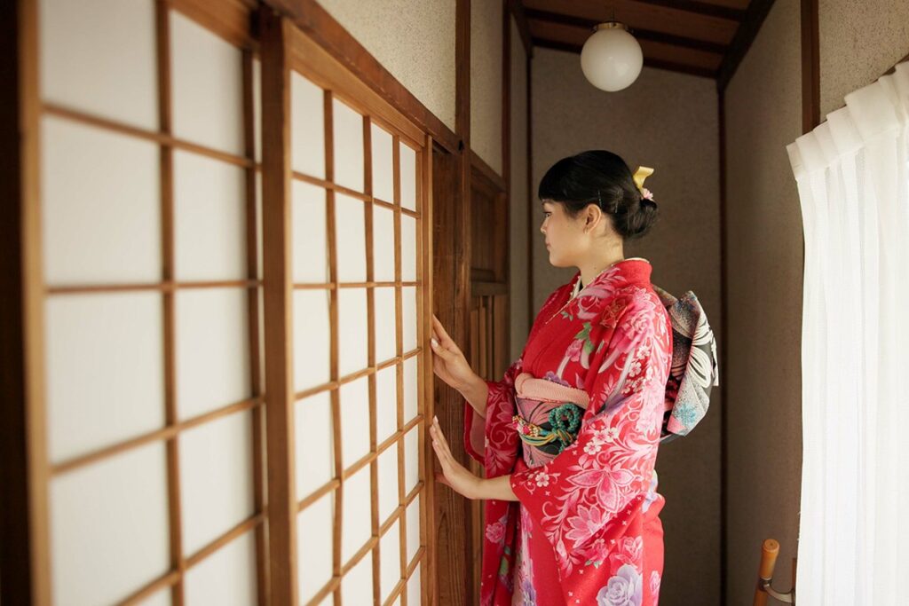 woman in kimono opening a traditional Japanese Shoji screen door