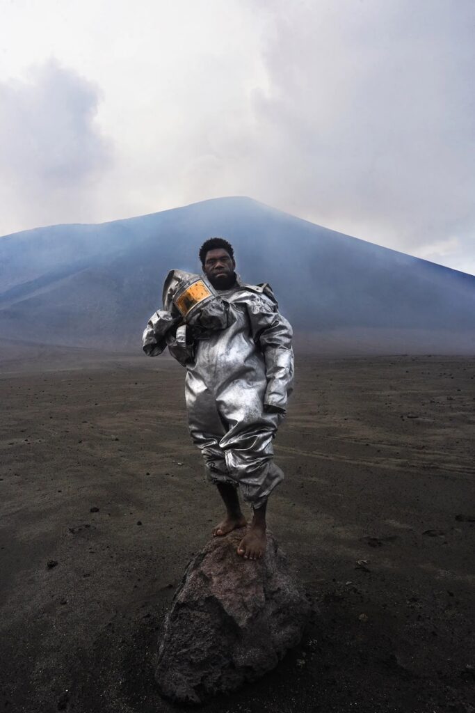 man in protective suit in front of a volcano
