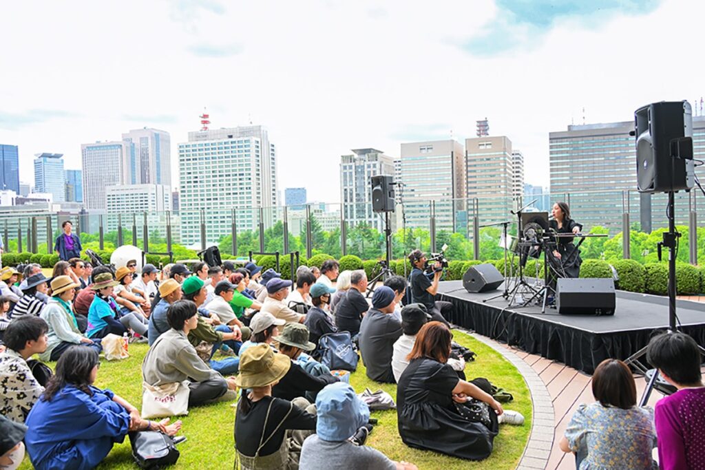 An intimate outdoor music experience on the outdoor garden at Tokyo Midtown Hibiya, with the Tokyo skyline in the backdrop