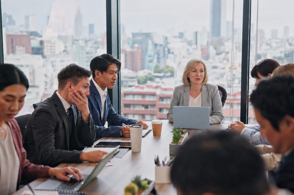 Japanese business people around a meeting room table with a foreign female leading the meeting