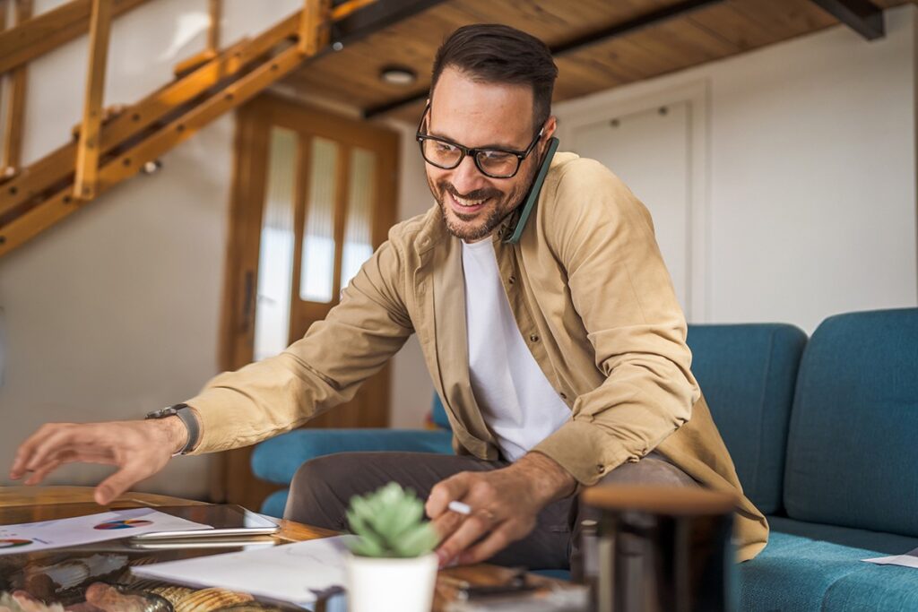 Man talking on the phone, looking over documents on the table, working remotely with trusted property investment partner in Japan