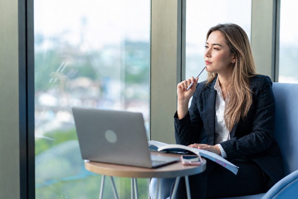 business woman with a textbook looking out of a window thinking