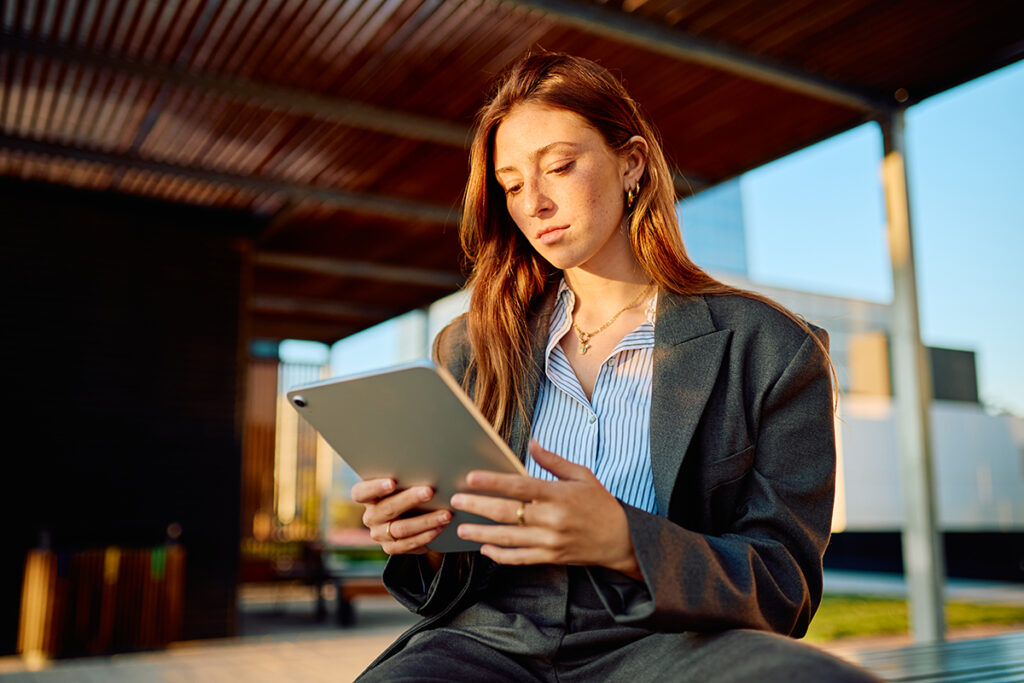Young professional woman working on digital tablet outdoors